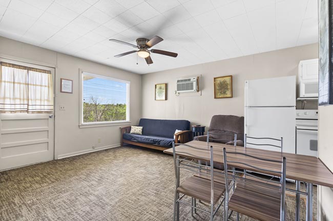 Cozy cabin living and dining area with futon, table, and kitchen appliances