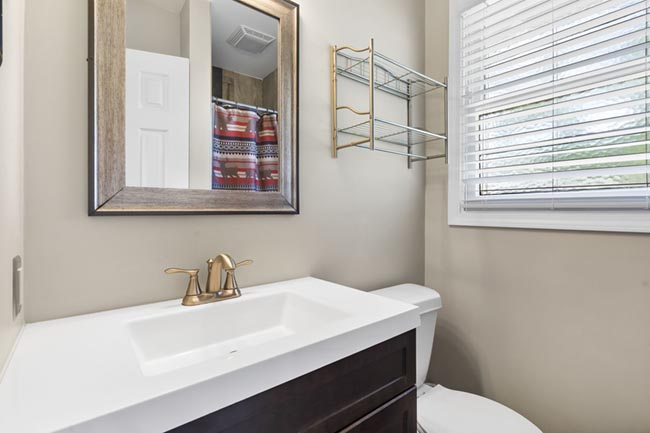 Bathroom vanity with mirror, sink, and window beside a toilet