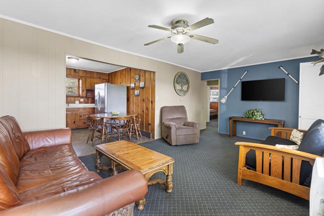 Cozy living room with leather sofa, recliner, TV, and dining area in the lake house