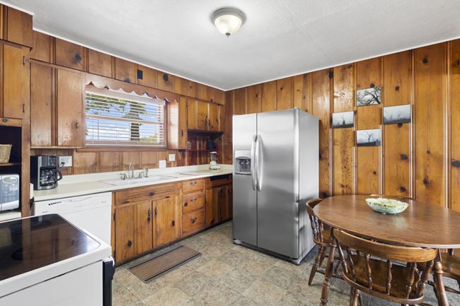 Wood-paneled kitchen with stainless steel refrigerator and round dining table