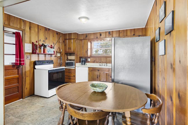 Cozy wood-paneled kitchen with dining table, stove, and refrigerator