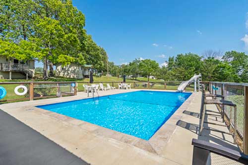 Outdoor resort swimming pool with lounge chairs and a waterslide on a sunny day